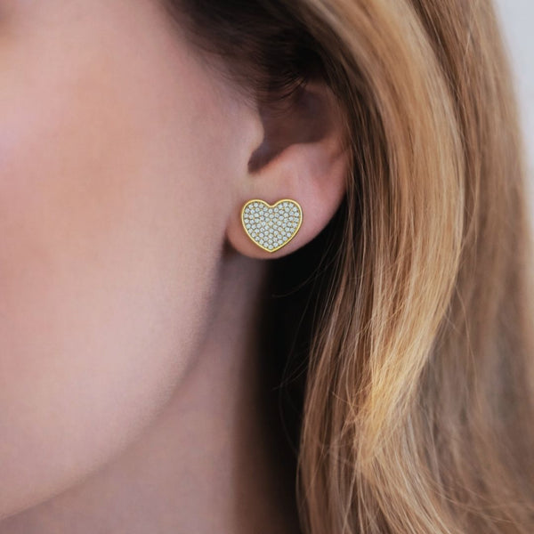 Model wearing Esmeé pavé heart diamond earrings in 18k yellow gold with traceable natural diamonds.