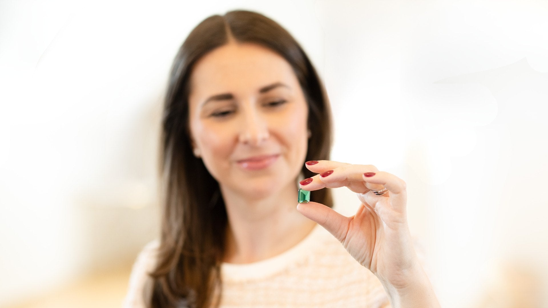 Sarah holding an emerald – expertise in natural gemstones and traceable diamonds